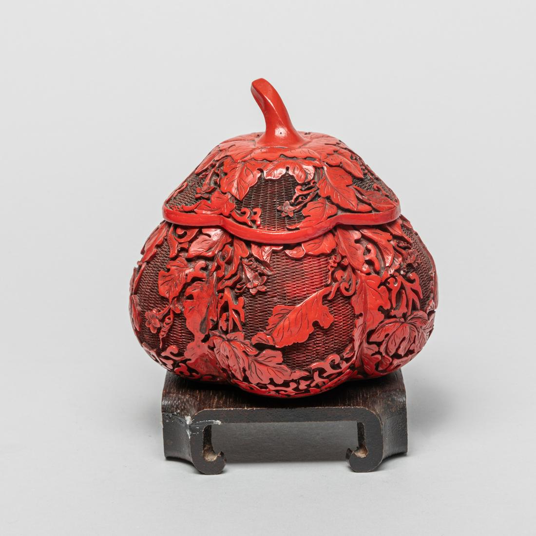 Special Form Chinese Cinnabar Box: Of pumpkin form, the body and lid exterior carved with leafy blossoming stems, with wood stand. 4.7inch H, 5inch W (w/o stand).