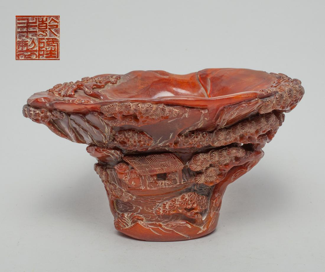 Collectible Chinese Carved HN Cup: The flared HN cup exterior carved in high relief with figures in a boat amid gnarled pine trees and craggy rockwork, the bottom carved with four characters. 7.6inch L, 5.2inch W, 4inch H.