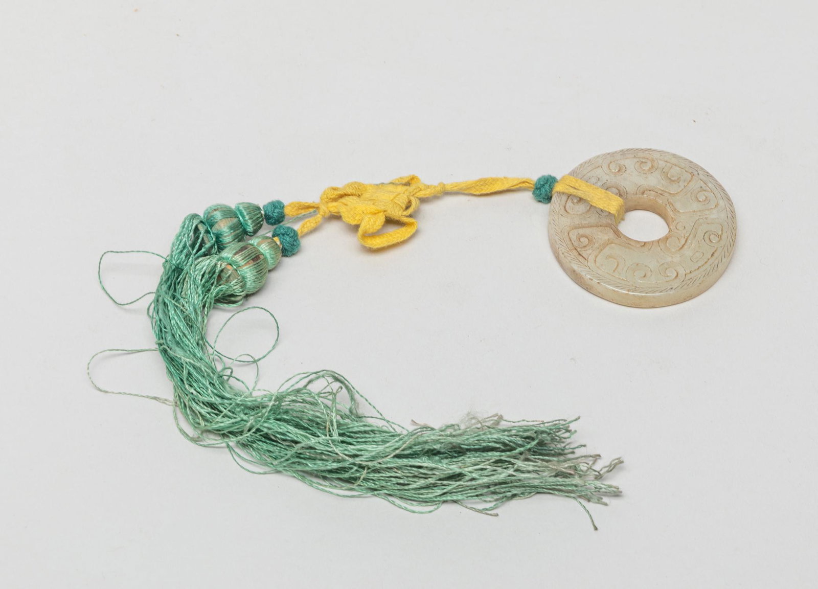 Chinese Jade Carved Bi: Of circular shape, carved on both sides in low relief with archaic beasts, the stone in mottled white tone, suspended on tassel. 2.1inch W (jade size).