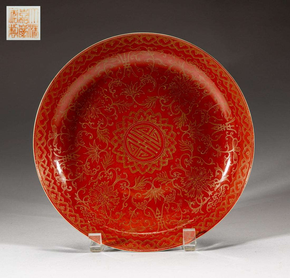 Chinese Gold Filled Porcelain Plate: The interior painted with lotus sprays surrounding central shou character, interspersed with bats and stylized shou characters, all against red ground, the exterior enameled with lotus scrolls, the bo