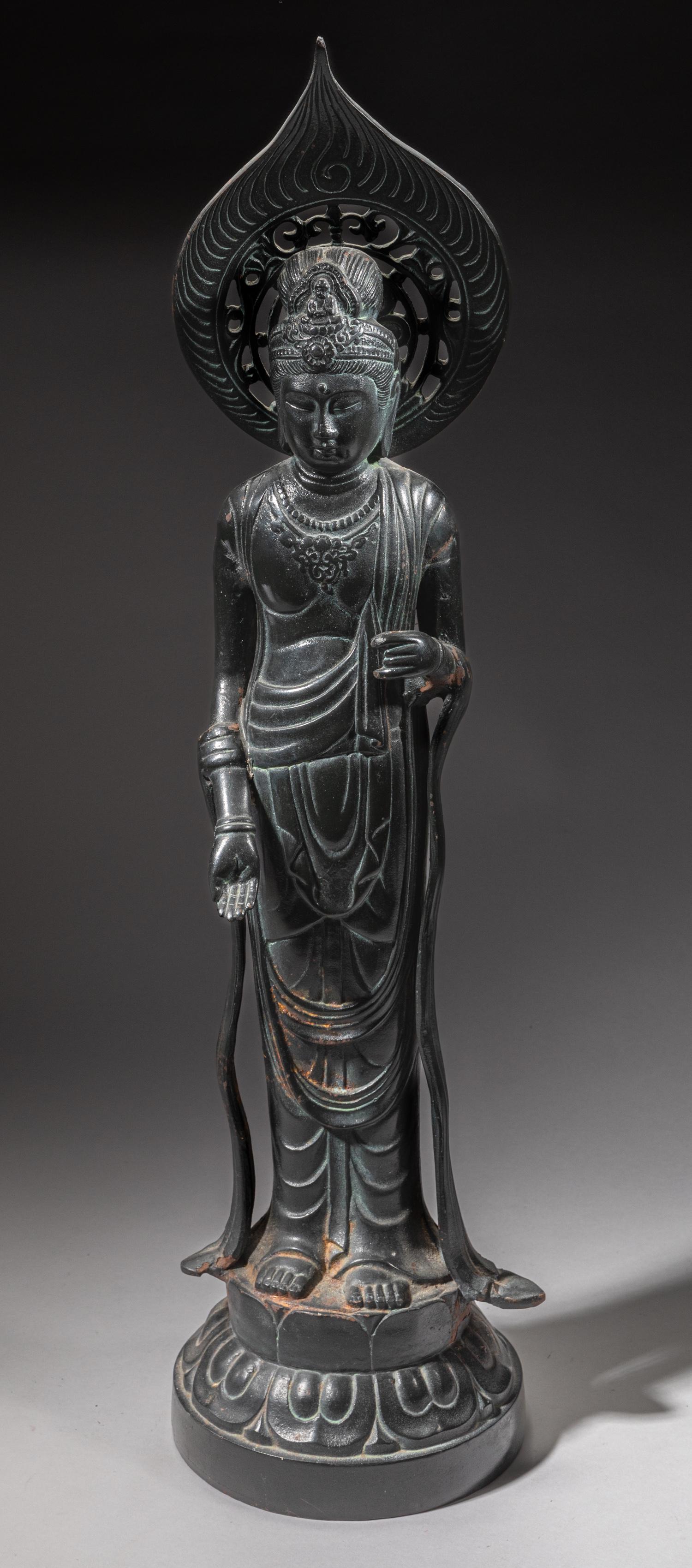 Tall Japanese Metal Buddha: Molded standing on a lotus base, dressed in loose-fitting robe, the face with serene expressions and slightly looking downwards, a flame a flame shape halo rearwards. Approx. 27-7 inch.