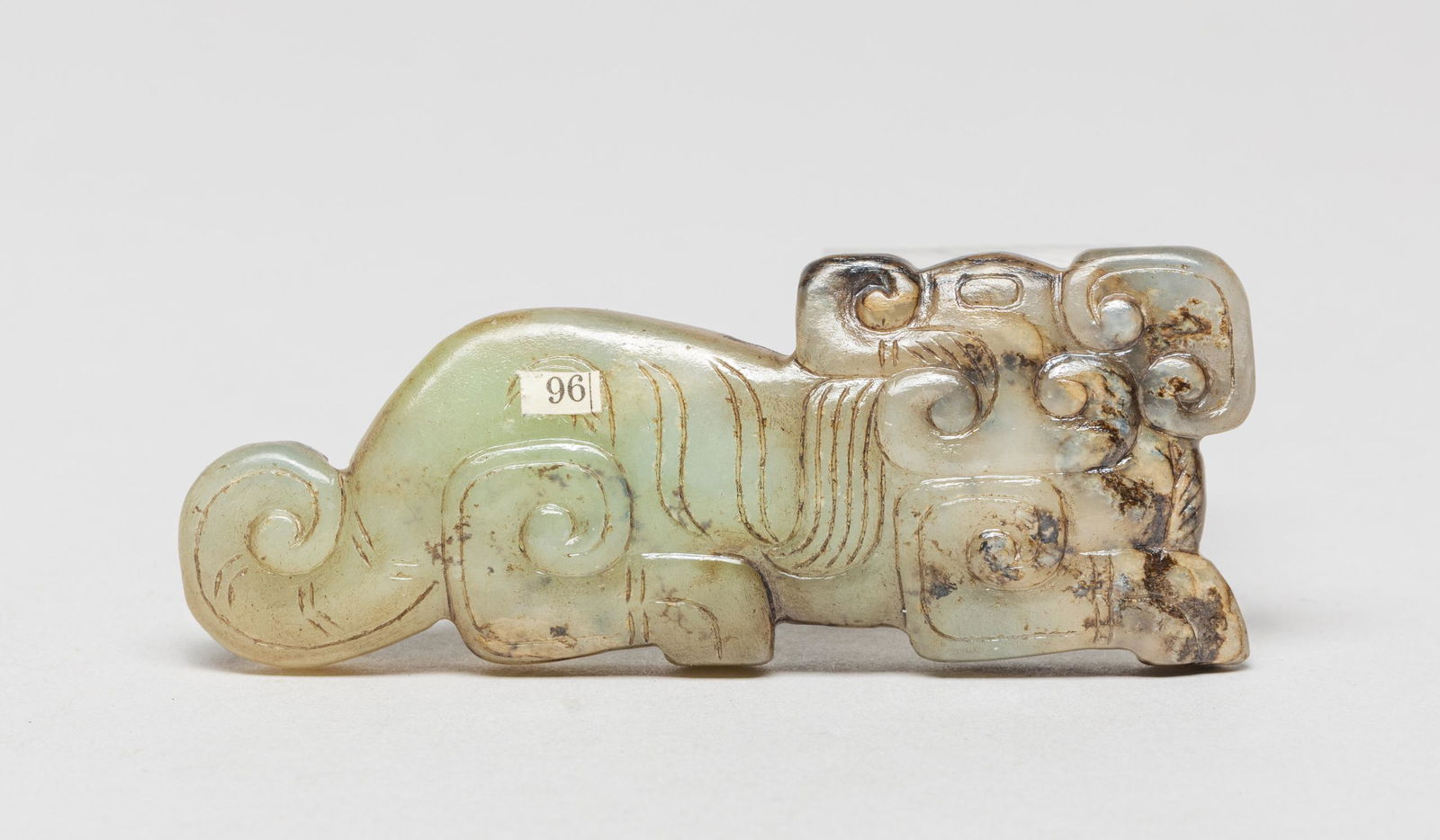 Chinese Russet Jade Beast: Worked in recumbent beast profile, its head turned sharply backwards, the stone of pale celadon color suffused with russet streaks . Approx. 3.2-1.2 inch.