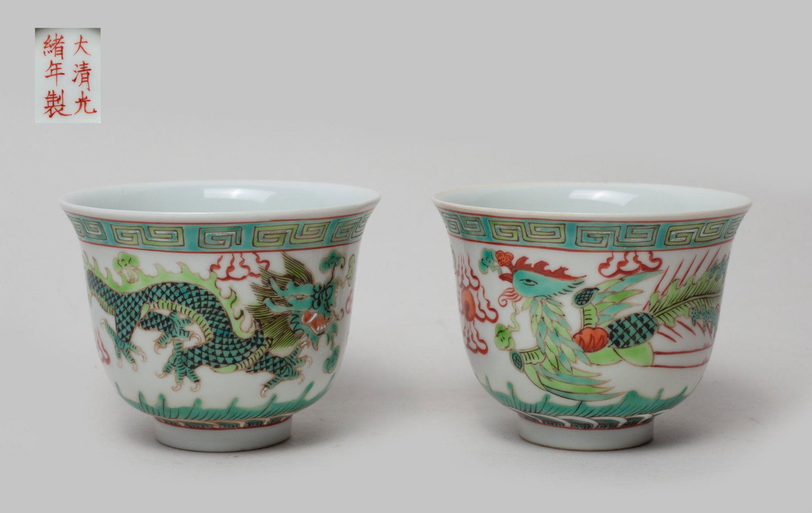 Pair Chinese Porcelain Cups: The cup exterior painted with a dragon and a phoenix chasing a flaming pearl amidst flames and above waves, the bottom marked with six characters. Approx. 3.1-2.4 inch (each).