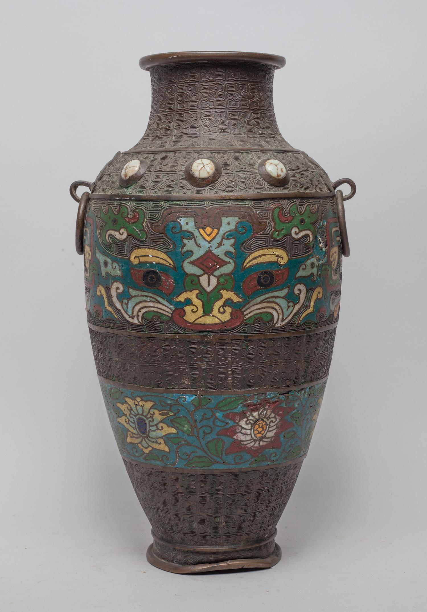 Antique Japanese Meiji Cloisonne Vase: The tall ovoid body with a waisted neck, flanked by a pair of mask loop handles, enameled with beast masks and lotus scrolls against an archaic motif ground. Approx. 14.1-7.5 inch.