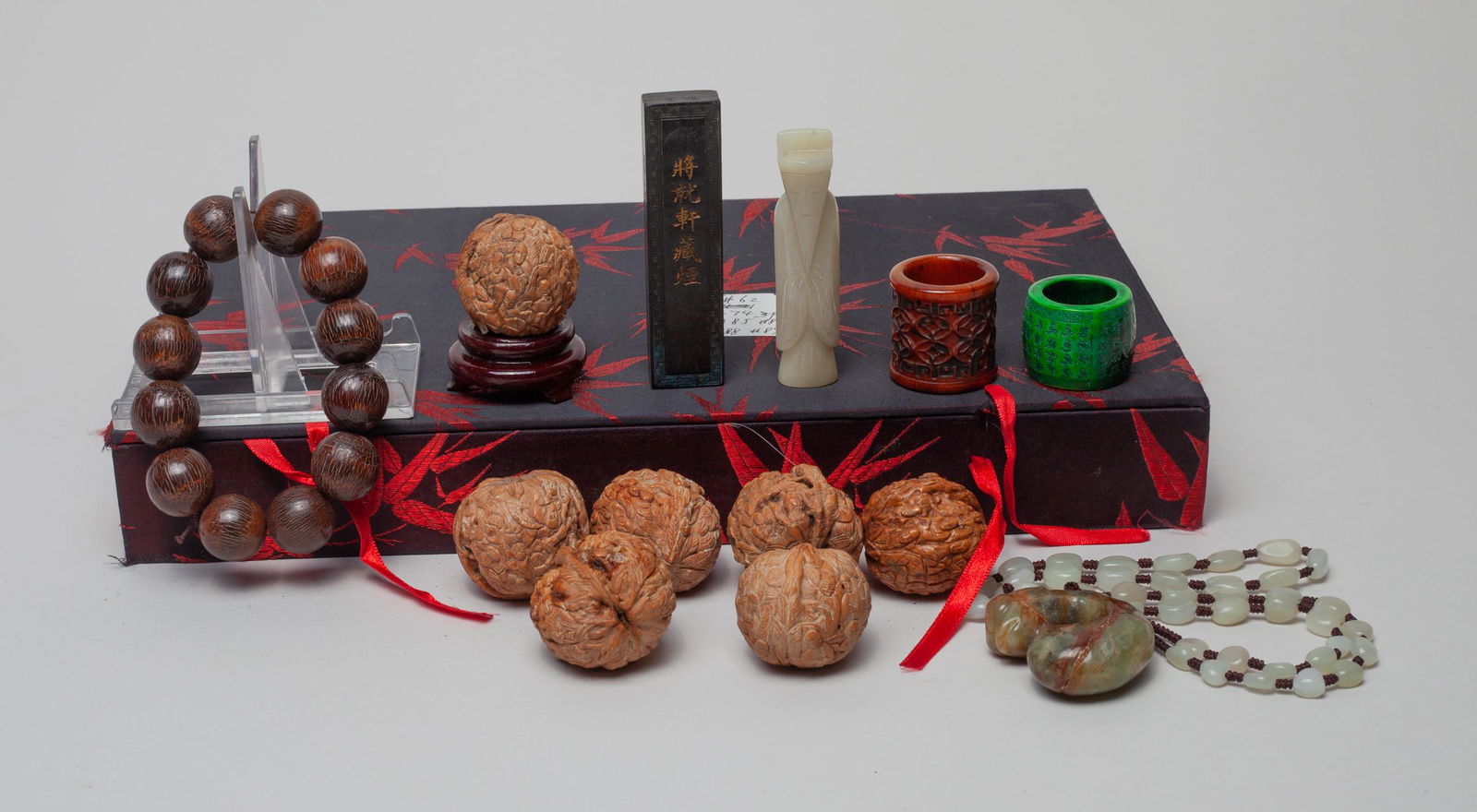 Chinese Nuts, Jade & Beads: Including carved nuts, prayer beads, thumb rings, jade carvings, a wood stand and an ink stick, with box. Approx. 3-0.7 inch (largest jade carving).