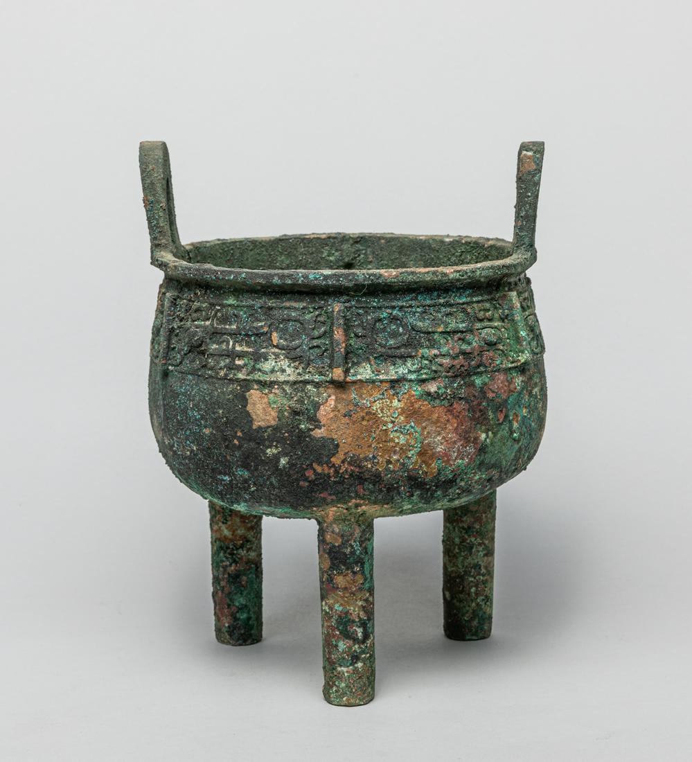 Collectible Chinese Bronze Censer: The deep U-shaped body cast below the everted rim and a pair of upright loop handles, above a register of three taotie masks bisected by flanges, supported on three columnar legs. 8.3inch H, 6.2inch W
