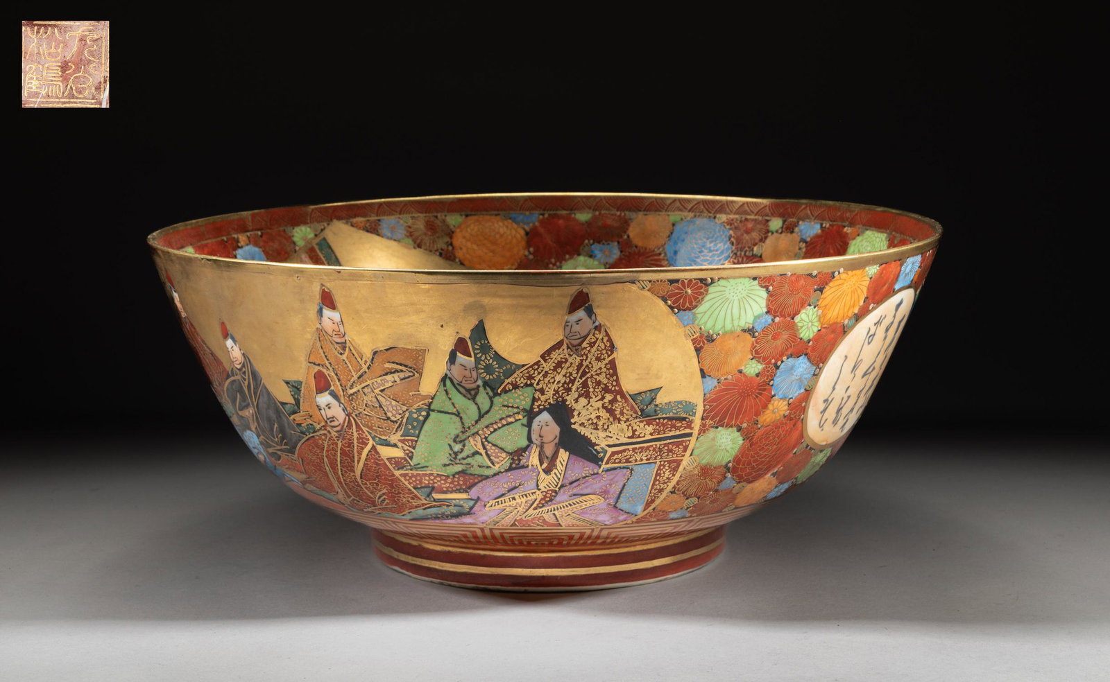 Massive Japanese Kutani Ware Porcelain Bowl: The bowl decorated with Japanese figural scene on the inside and out, among dense flowers, the bottom inscribed with a seal mark. Approx. 16.5-7 inch.