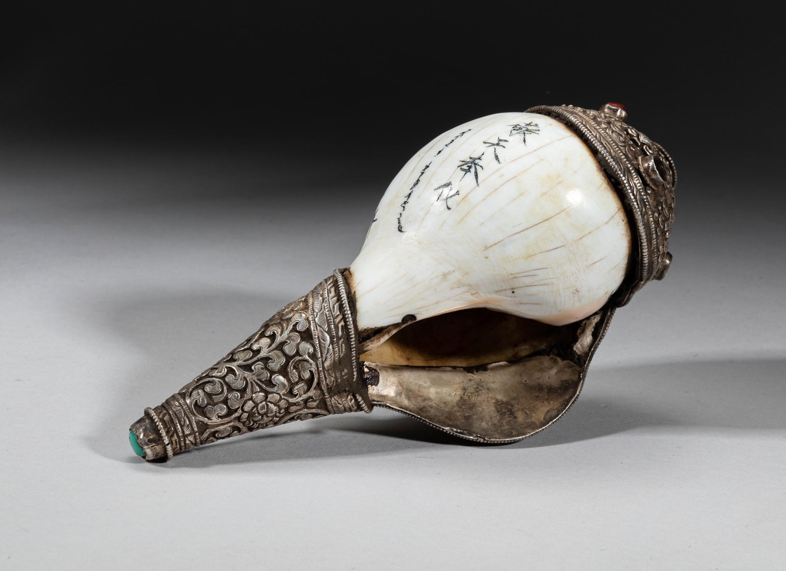 Chinese Sino-Tibetan Conch: The Sino-Tibetan type conch with metal rim and tip, cast with flower scrolls and inset with stone, inscribed with related passages, Approx. 7.5-3.3-2.7 inch.