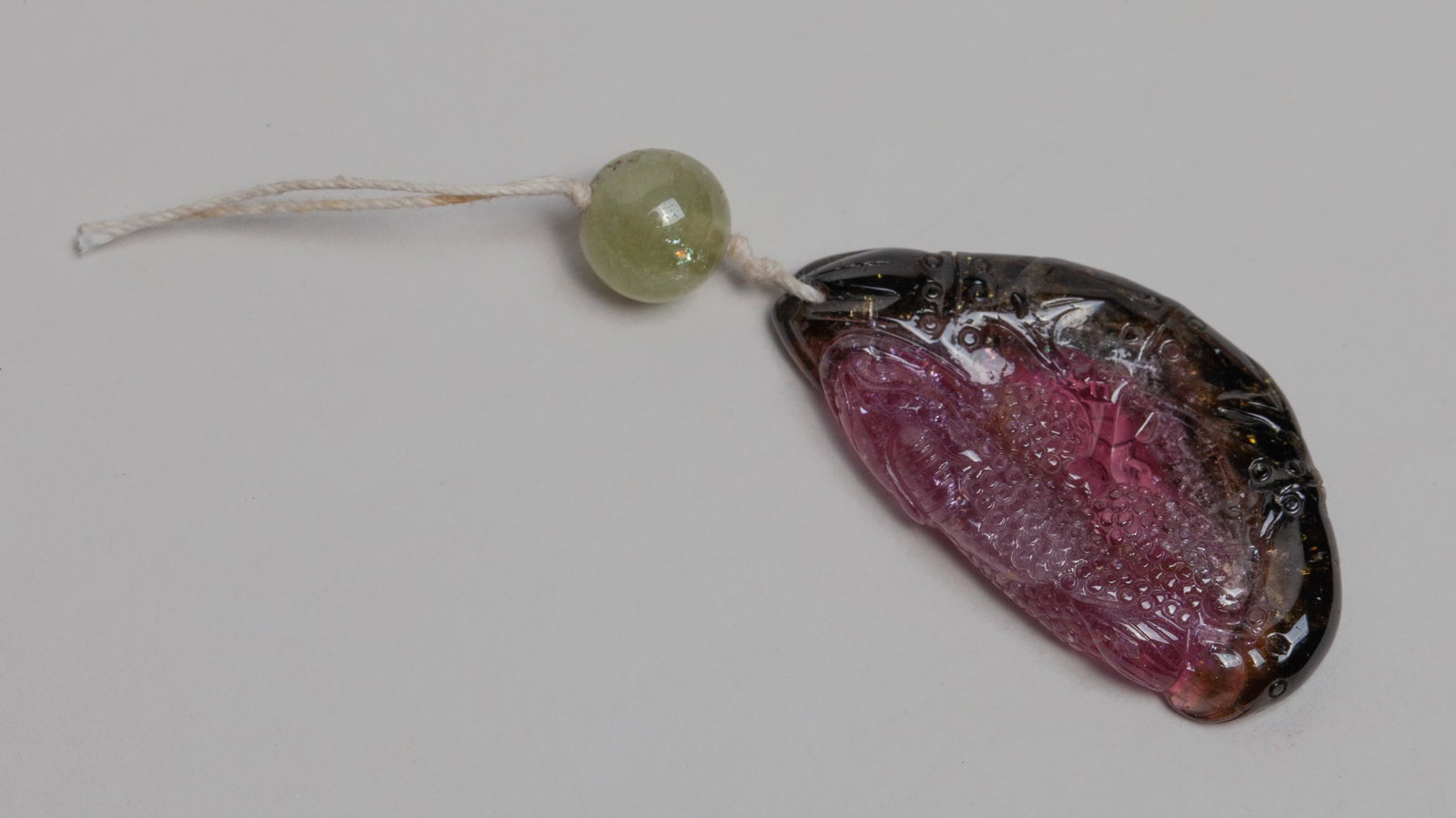 Chinese Watermelon Tourmaline Pendant: Collectible watermelon tourmaline carved with toad, coin and lotus shoot, with a gemstone bead. Approx. 1.7-0.9 inch (tourmaline size).