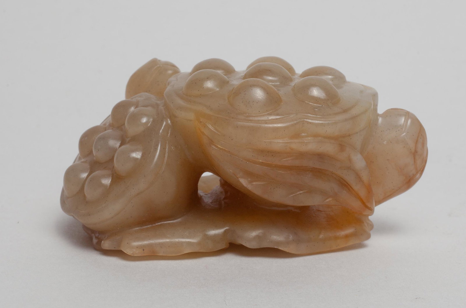 Chinese Russet Jade Lotus: Naturalistically carved as lotus seedpods and buds issuing from stem with lotus leaves forming the base. Approx. 2.8-1.7-1.3 inch.