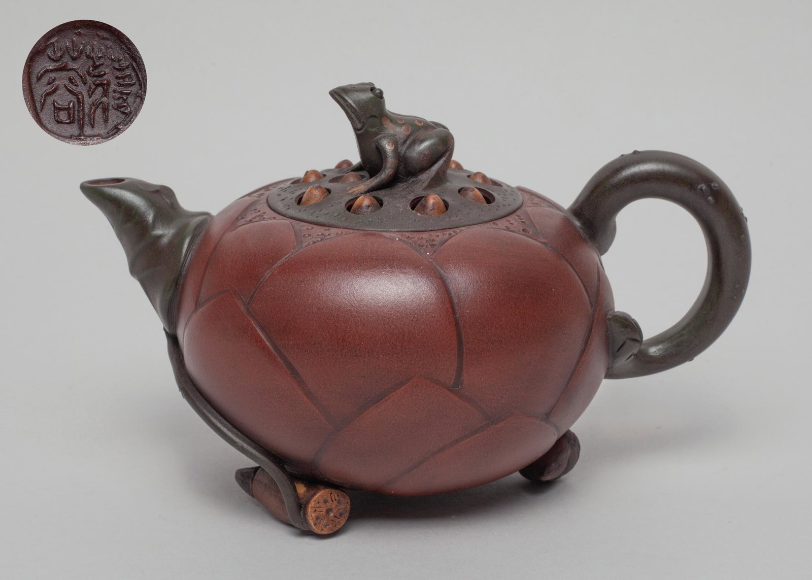 Vintage Chinese Yixing Zisha Tea Pot: The tea pot modeled in lotus form resting on aquatic fruits, the lid carved in lotus seedpod form with a frog finial, the bottom with a circular mark. Approx. 6.5-4.3-4.1 inch.
