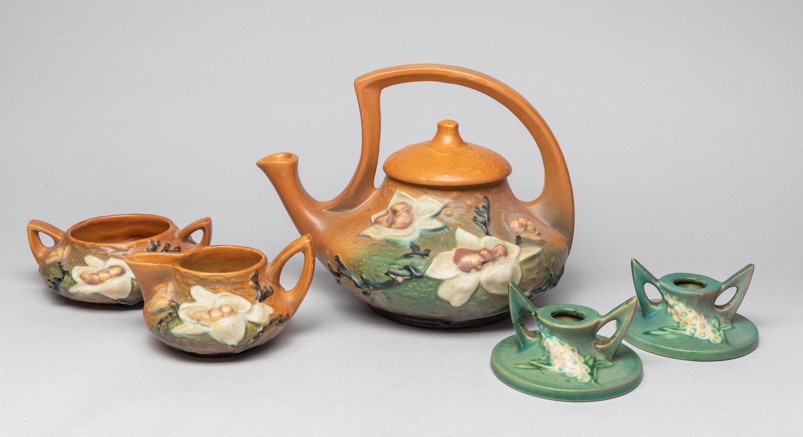 Roseville Type Stoneware Pieces: Including a pot, a creamer, a sugar bowl and 2 stands, carved with flowers, the bottom marked Roseville U.S.A. Approx. 7.7-9.5-8 inch.