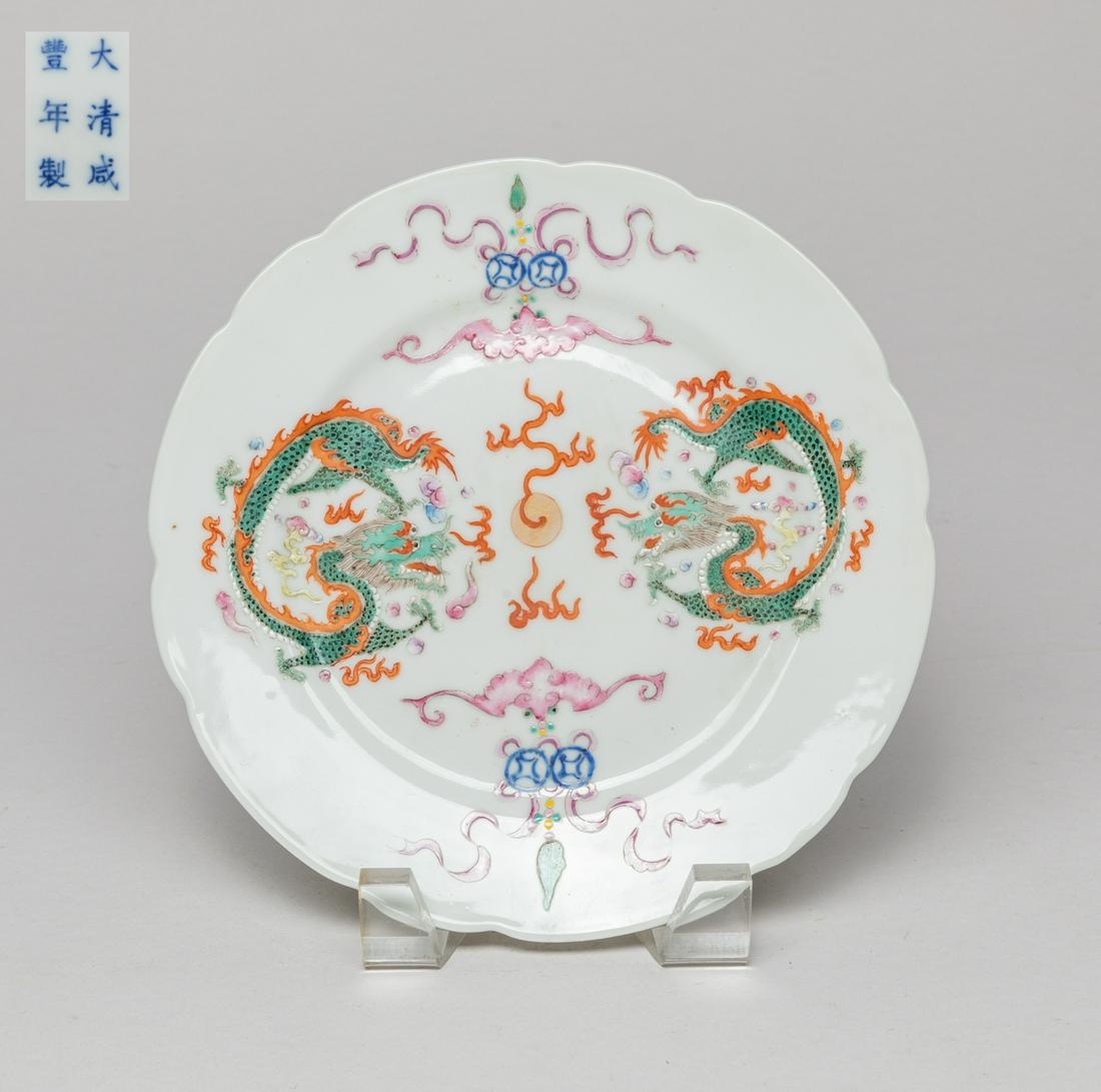 Chinese Famille Rose Porcelain Plate: The interior enameled with dragons pursuing a flaming pearl amidst flames and clouds, spaced with beribboned coins and bat, the bottom marked with six characters. Approx. 7.3inch W.