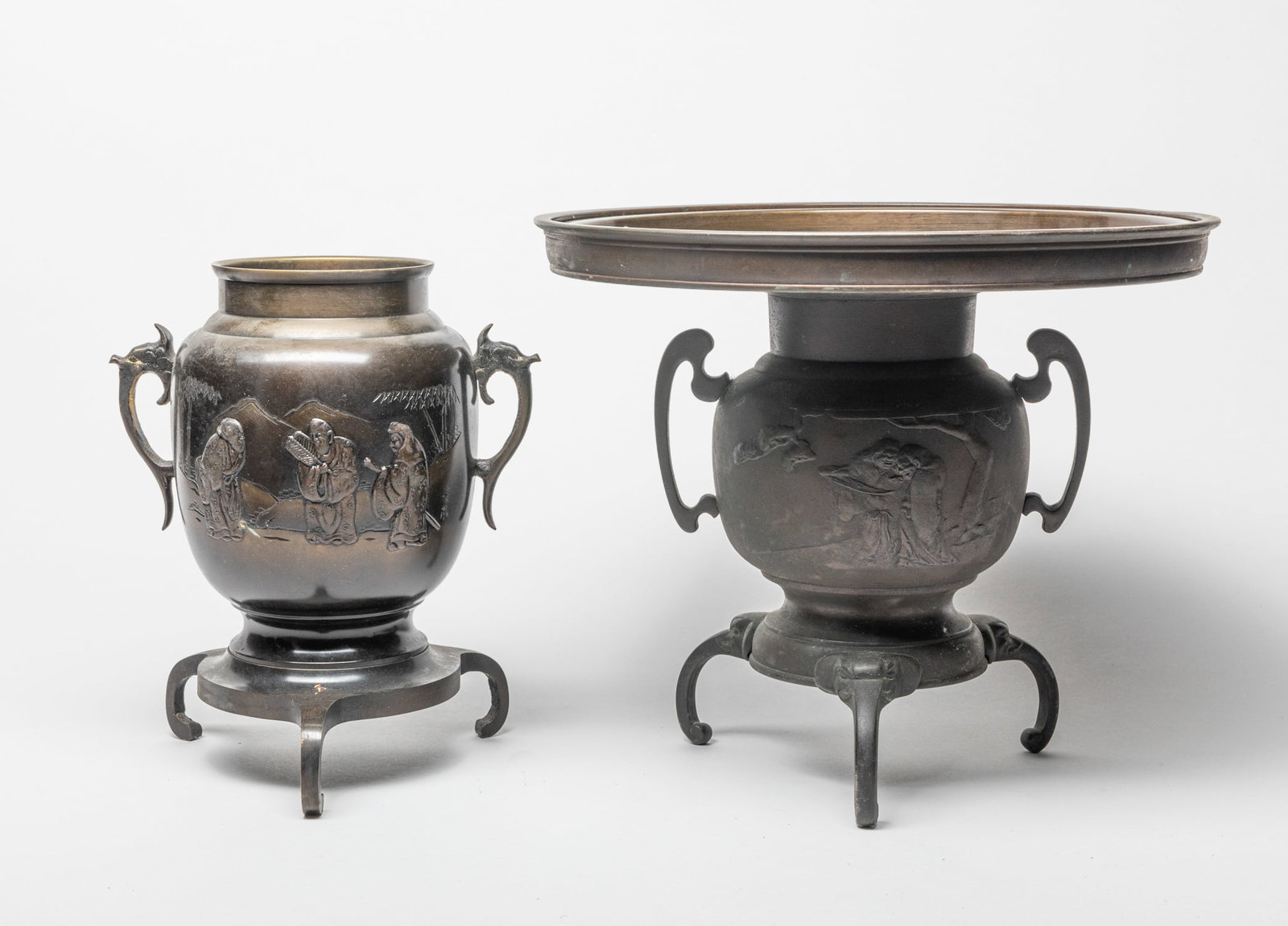 Antique/Vintage Japanese Vase: Each of ovoid form resting on three incurved legs, flanked with a pair of stylized handles, cast with figures in landscape, supporting large flat circular plate. 11.8inch W, 10.2inch H (larger).