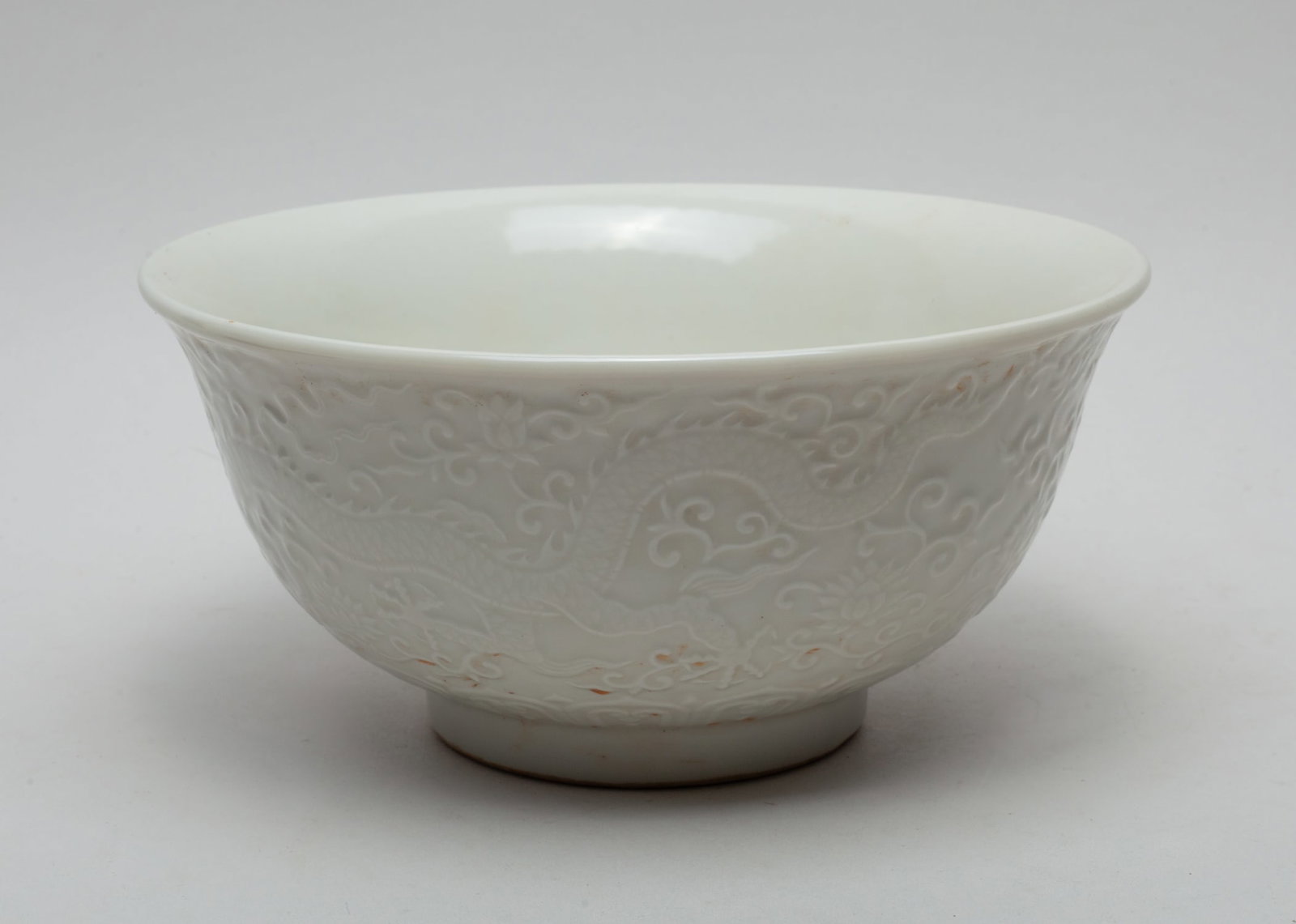 Massive Chinese Blank De Porcelain Bowl: The bowl exterior carved with dragons amidst lotus scrolls, covered overall in creamy glaze. Approx. 8.6-4.1 inch.