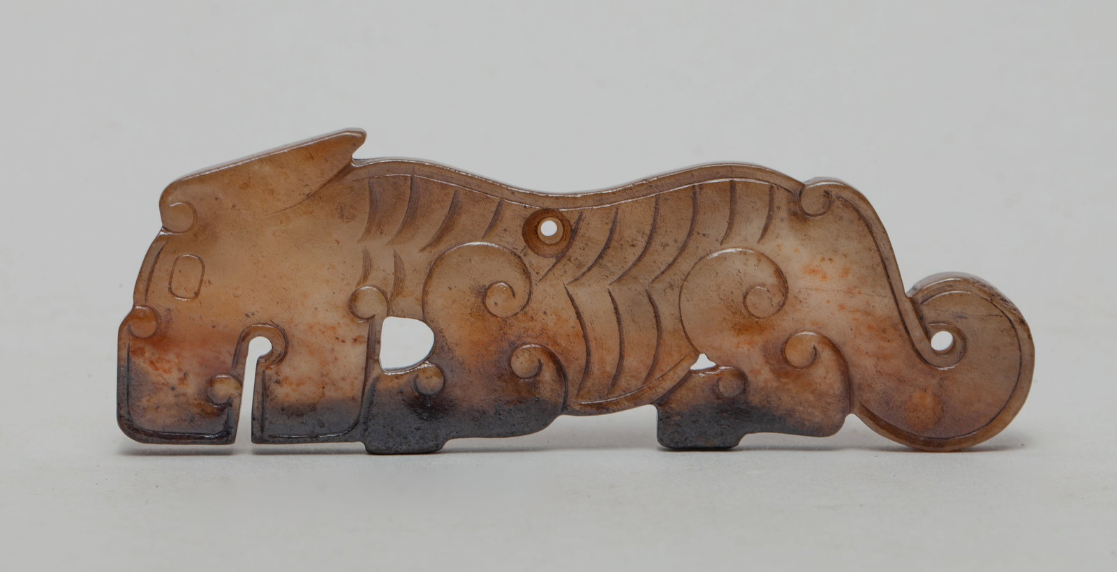 Chinese Russet Jade Carving of Beast: Russet jade carving worked in recumbent beast profile, pierced at the back, tail and leg. Approx. 3.6-1.3 inch.