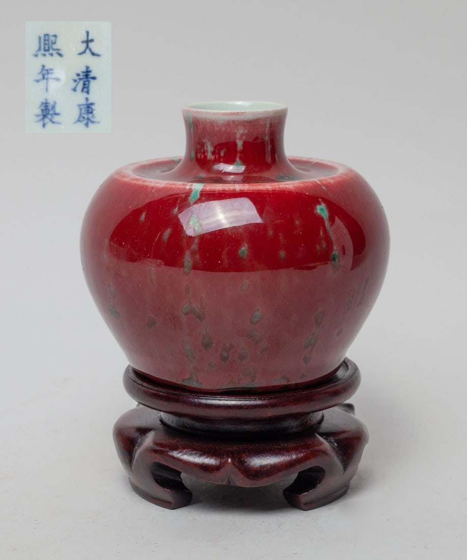 Chinese Flambe Glazed Porcelain Water Pot: The porcelain water pot exterior covered in mottled red glaze suffused with green splashes, the bottom marked with six characters, with wood stand. Approx. 3.9-3.4 inch (w/o stand).