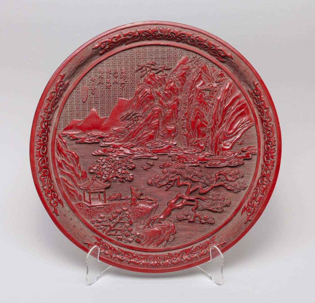 Chinese Export Cinnabar Plate: The interior carved with scholar in mountainous landscape, with pine tree and pavilion. Approx. 12.4inch W.