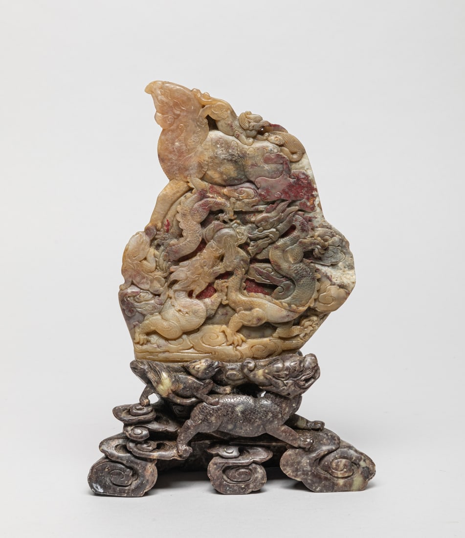 Chinese Chicken Blood Stone Sculpture: Collectible Chinese chicken blood stone table sculpture carved with dragon and beast amidst clouds. Approx. 9-6.2-1.8 inch.