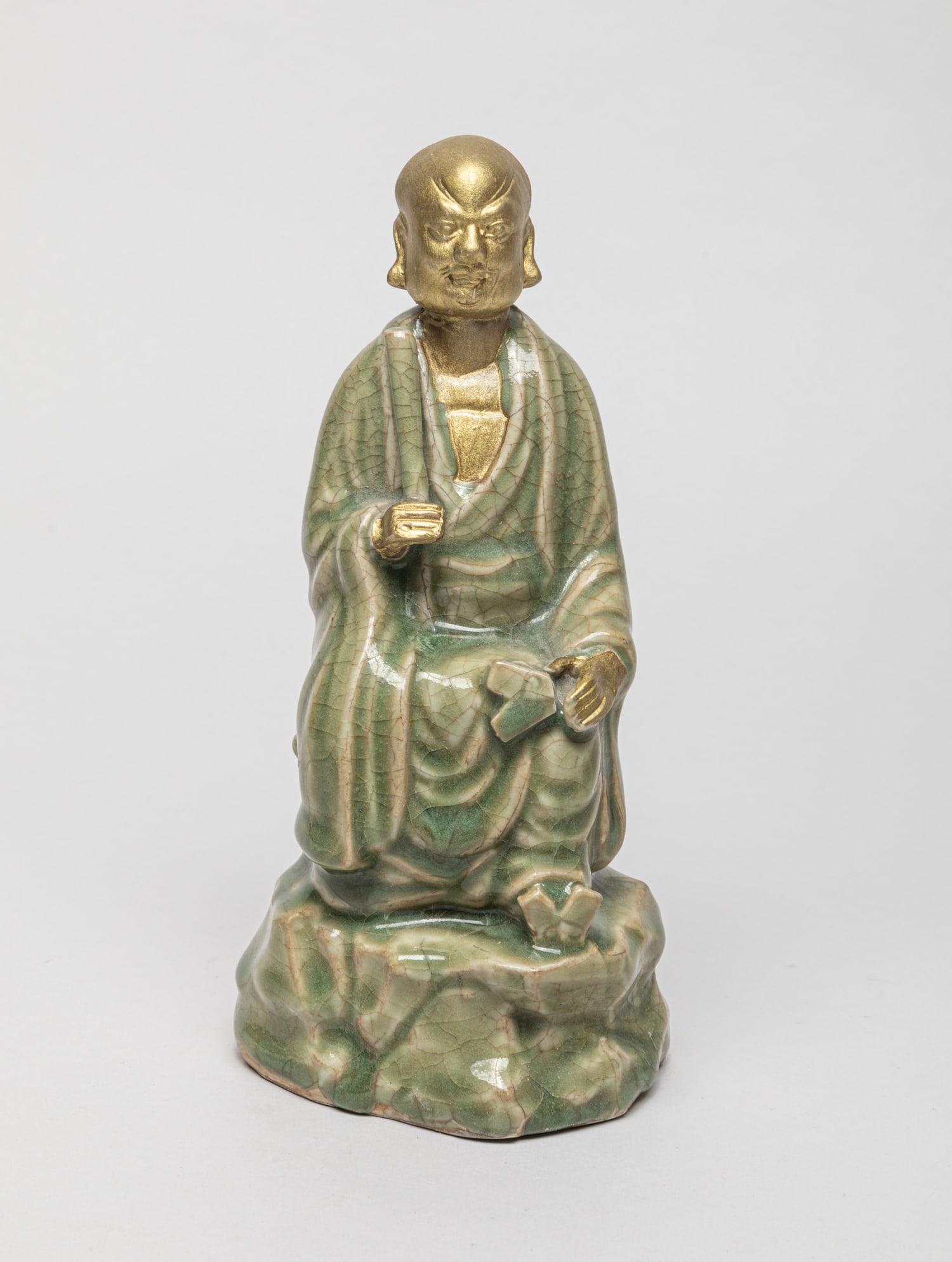 Korean Porcelain Sculpture of Buddha: Korean hollow porcelain Buddha sculpture, the body and base covered in crackled olive-green glaze, the head and hands unglazed. Approx. 8-3.8-3.2 inch.