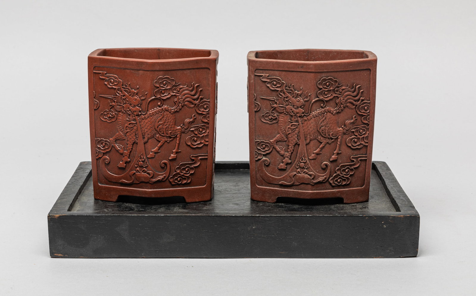 Chinese Zisha Vases w/ Wood Stand: Two zisha vases carved with qilin spraying smoke amidst clouds, the bottom with mark, , with a wood stand. Approx. 4.4-3.9-3 inch (vase size).