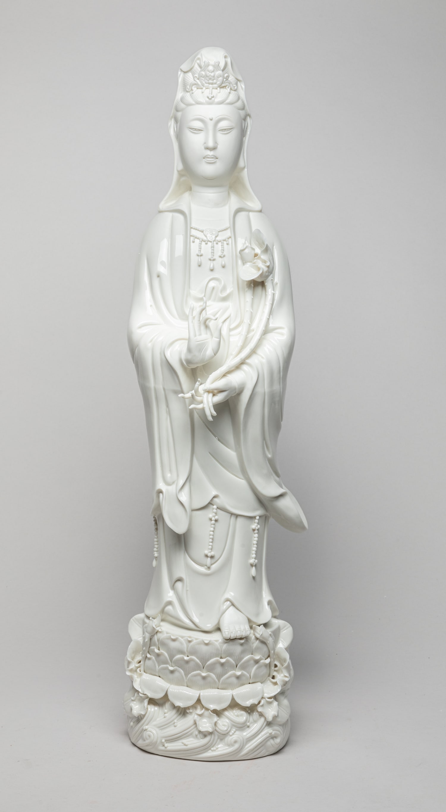 Chinese Tall Blank De Porcelain Figure: Tall Chinese white-glazed porcelain Kuanyin sculpture, standing on a lotus base, the left hand holding lotus and right hand in vitarka mudra. Approx. 26.7-6.2-5.5 inch.