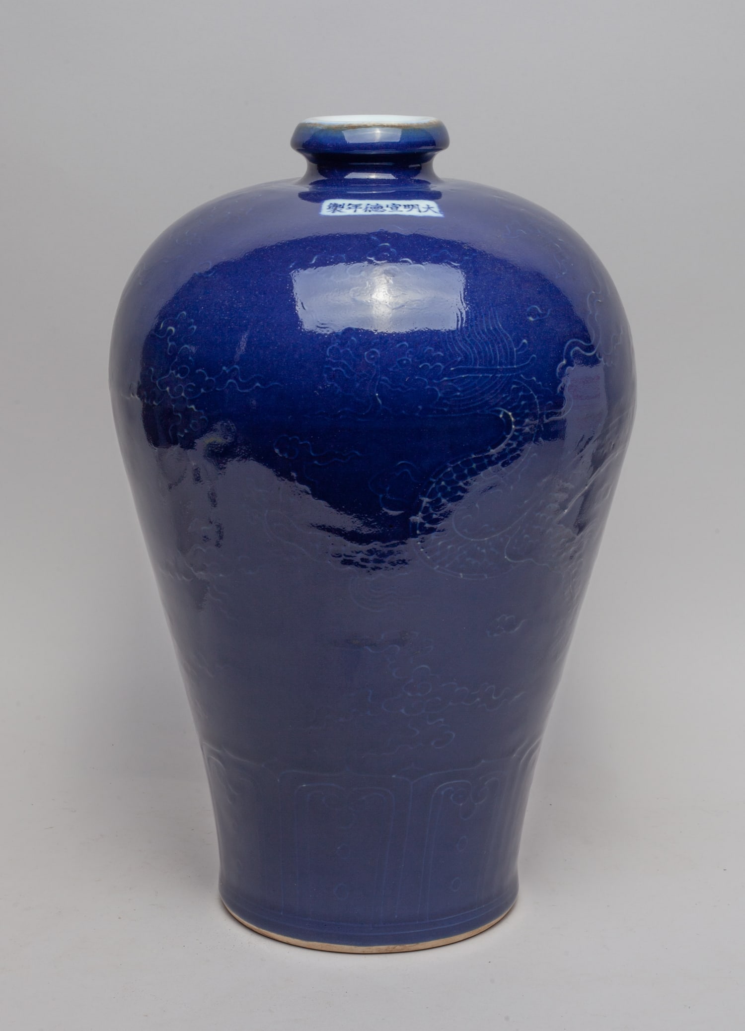 Tall Chinese Blue Glazed Porcelain Vase: Of baluster form with a short waisted neck, the exterior carved in low relief with dragon amidst clouds, glazed in cobalt blue color, marked with six characters. Approx. 14.6-9 inch.