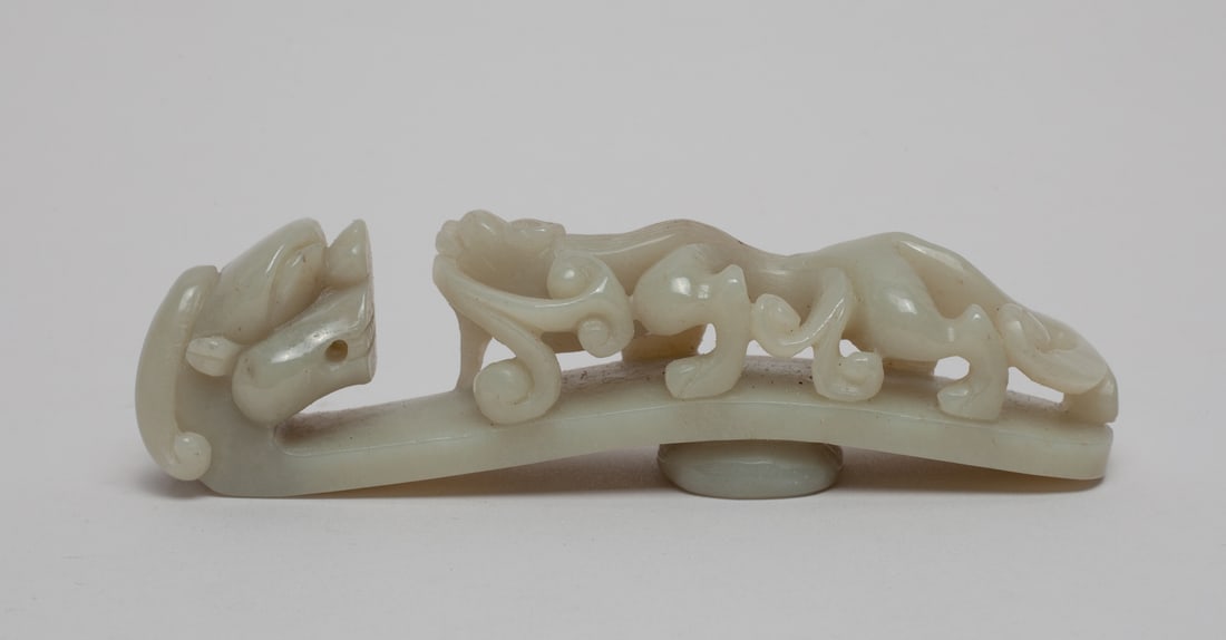 Large Chinese Jade Belt Buckle: Carved and reticulated with a sinuous chilong facing the dragon head terminal, the underside with a circular knob. Approx. 4.5-1-1.2 inch.