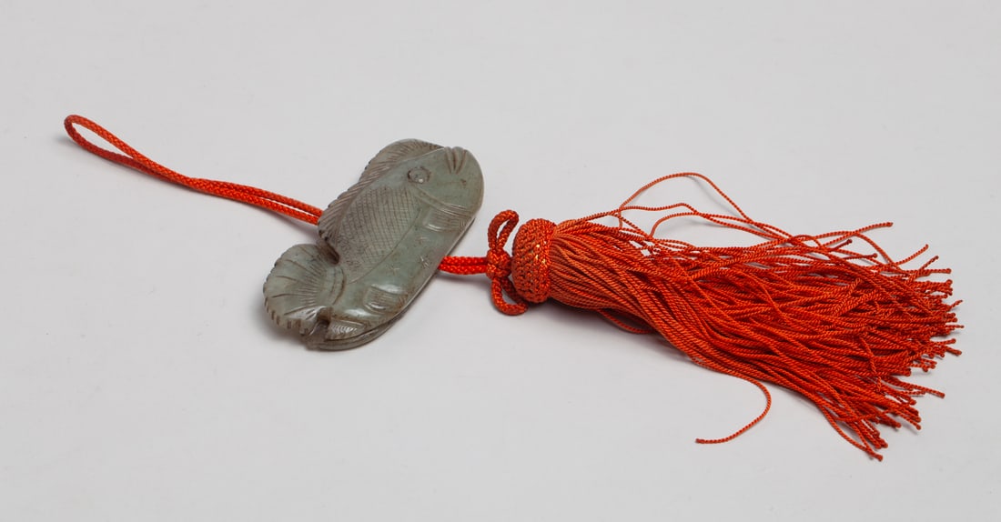 Chinese Manchu Jade Pendant: Chinese grayish celadon jade pendant of flat shape, either side carved with fish, with tassel. Approx. 3.4-1.4 inch.
