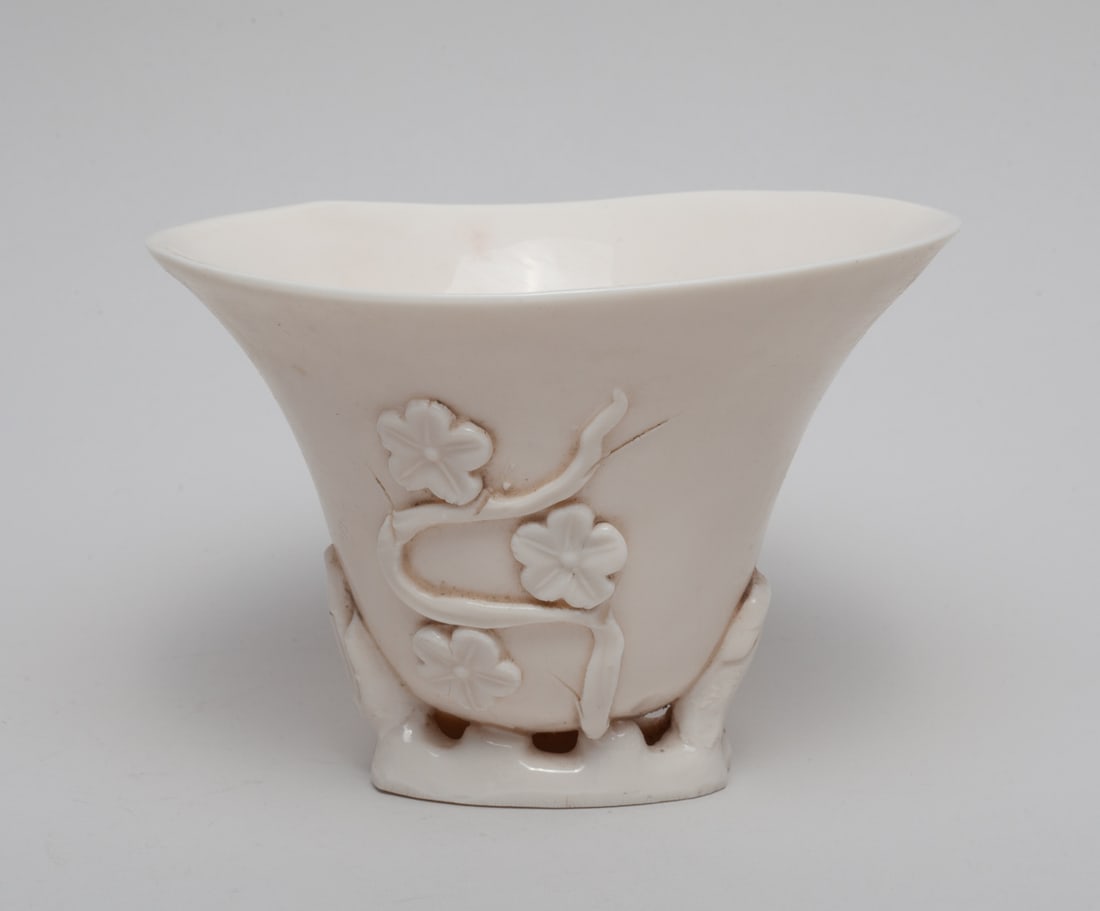 Chinese Blank De Porcelain Cup: The cup exterior carved in high relief with flower stems, the stems forming the base, covered overall in creamy white glaze. Approx. 5.3-4.8-3.8 inch.