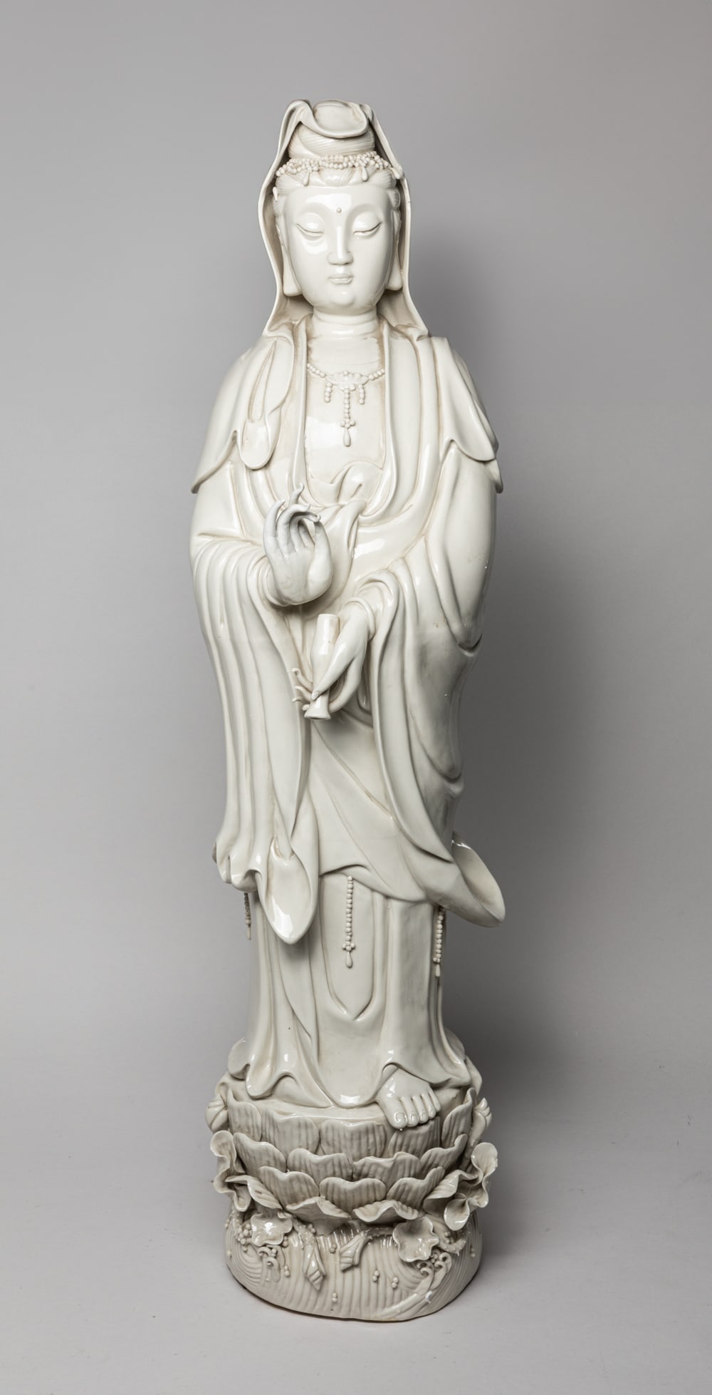 Tall Chinese Blank De Porcelain Kuanyin: Tall Chinese white-glazed porcelain Kuanyin, the left holding a bottle and right hand in vitarka mudra, the face with serene expression. Approx. 33-7.5-6.7 inch.