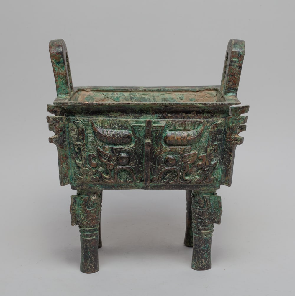 Estate Chinese Bronze Censer: Of rectangular section with four legs and two handles, each side carved with a taotie mask divided by raised flange. Approx. 9-7.7-5.4 inch.