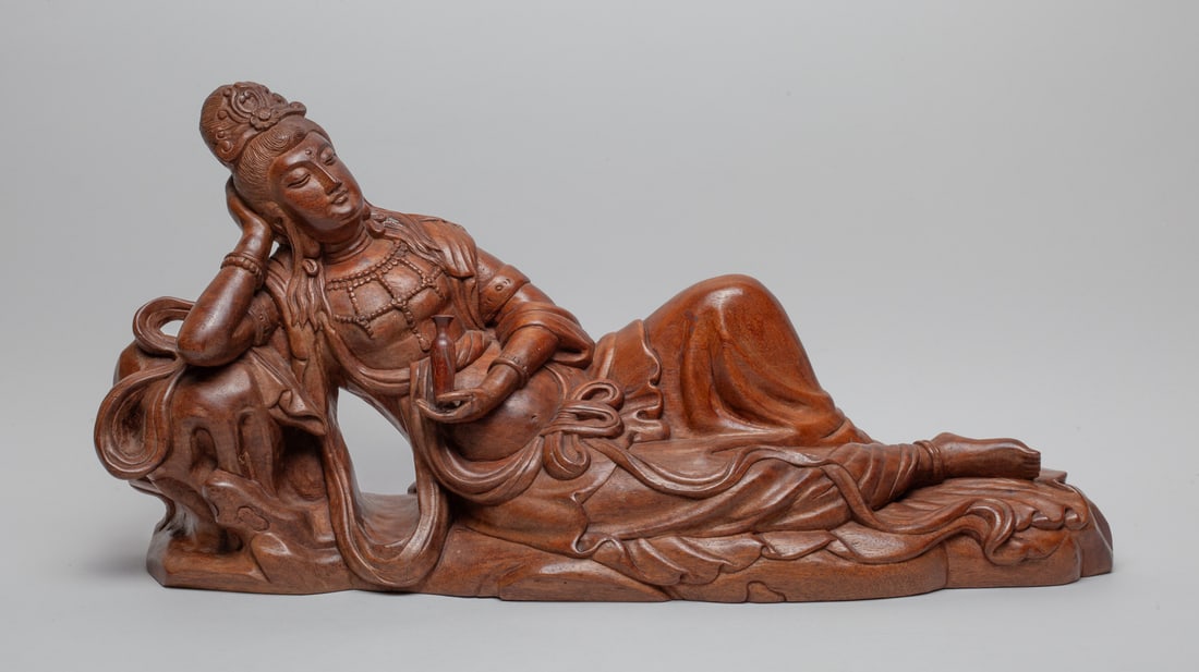 Large Chinese Wood Carved Kuanyin: Chinese wood Kuanyin carved lying on her side, with left hand holding a bottle, wearing a long flowering robe. Approx. 22-11-6 inch.