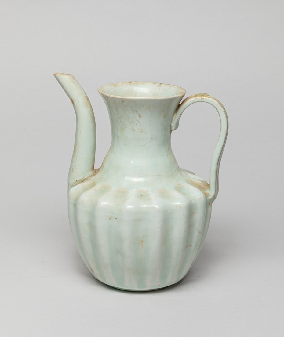 Chinese Hutian Porcelain Pot: A collectible Chinese Hutian porcelain pot with a curved handle and slender spout, the body raising from a circular base to a body with multiple grooves and to a neck and to an outward-flaring rim, wi