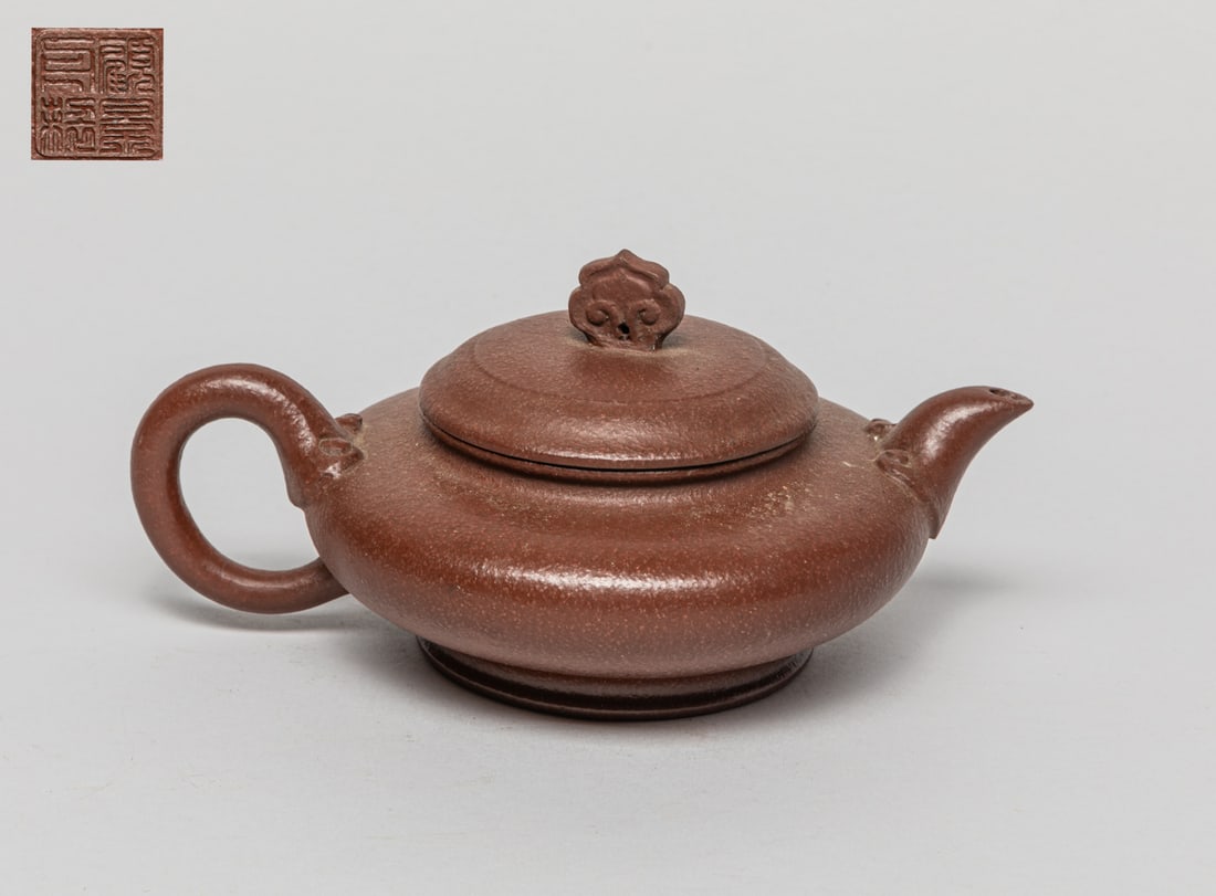 Chinese Yixing Zisha Tea Pot: Collectible Yixing Zisha tea pot in suppressed globular form, with a curve handle and a short tea pot spout, the circular cover with a flower-shape knob on top, bottom with two seals. Approx. 7.2-5.5-
