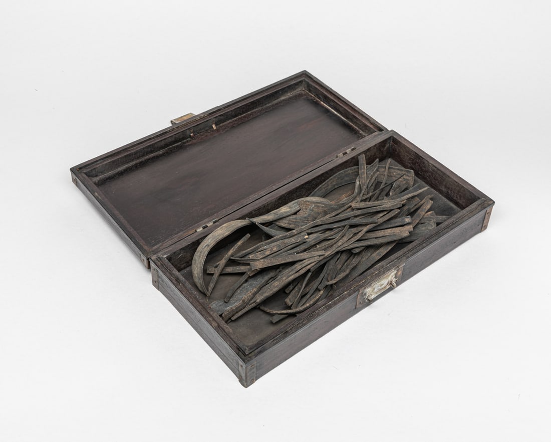 Chinese Wood Book w/ Wood Box: A box of collectible Chinese wood books, each piece inscribed with Chinese characters, with bent or distorted pieces, with a box. Approx. 12.5-5.7-2.5 inches (Box).