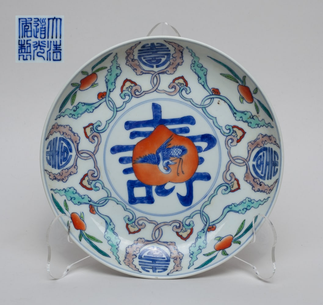 Chinese Export Porcelain Plate: The glazed Chinese export porcelain plate painted with a circular Shou symbol in center, and a dancing crane in front of a peach, a flower motif with four Shou symbol on surface, exterior painted with
