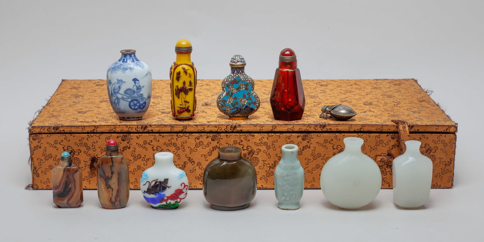 Estate Box of Chinese Snuff Bottles: A box of 12 Chinese snuff bottle, composed of porcelain, glass, Chinese Cloisonne, agate and metal, half with stopper, with a box. Sizes vary. The Estate of Store Closed Sale in DTLA.