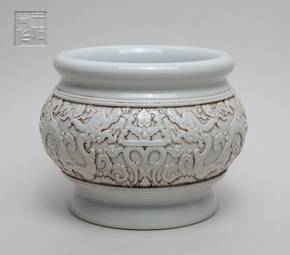 Chinese Modeled Blank De Porcelain Washer: One collectible Chinese blank De porcelain washer, the body carved with a band of sinuous dragons, the bottom with a seal mark. Approx. 6.3-5.0 inches.