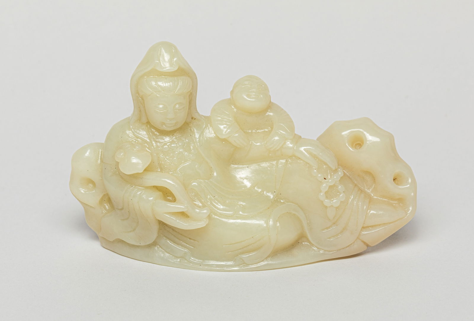 Chinese Jade Carving of Kuanyin: In a reclining pose, the Kuanyin holding a Linzhi in one hand, and with another figure climbing onto its arm. Approx. 4.8-1.8-3.3 inches.