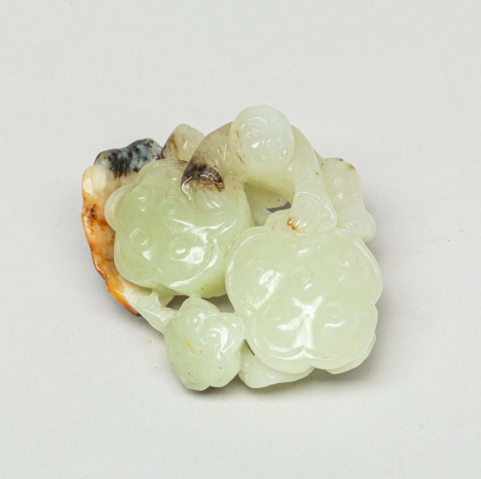 Chinese Russet Jade Lotus Sculpture: Carved with a figure climbing onto two lotus pods below a lotus leaf. Approx. 3.2-2.7-2.0 inches.