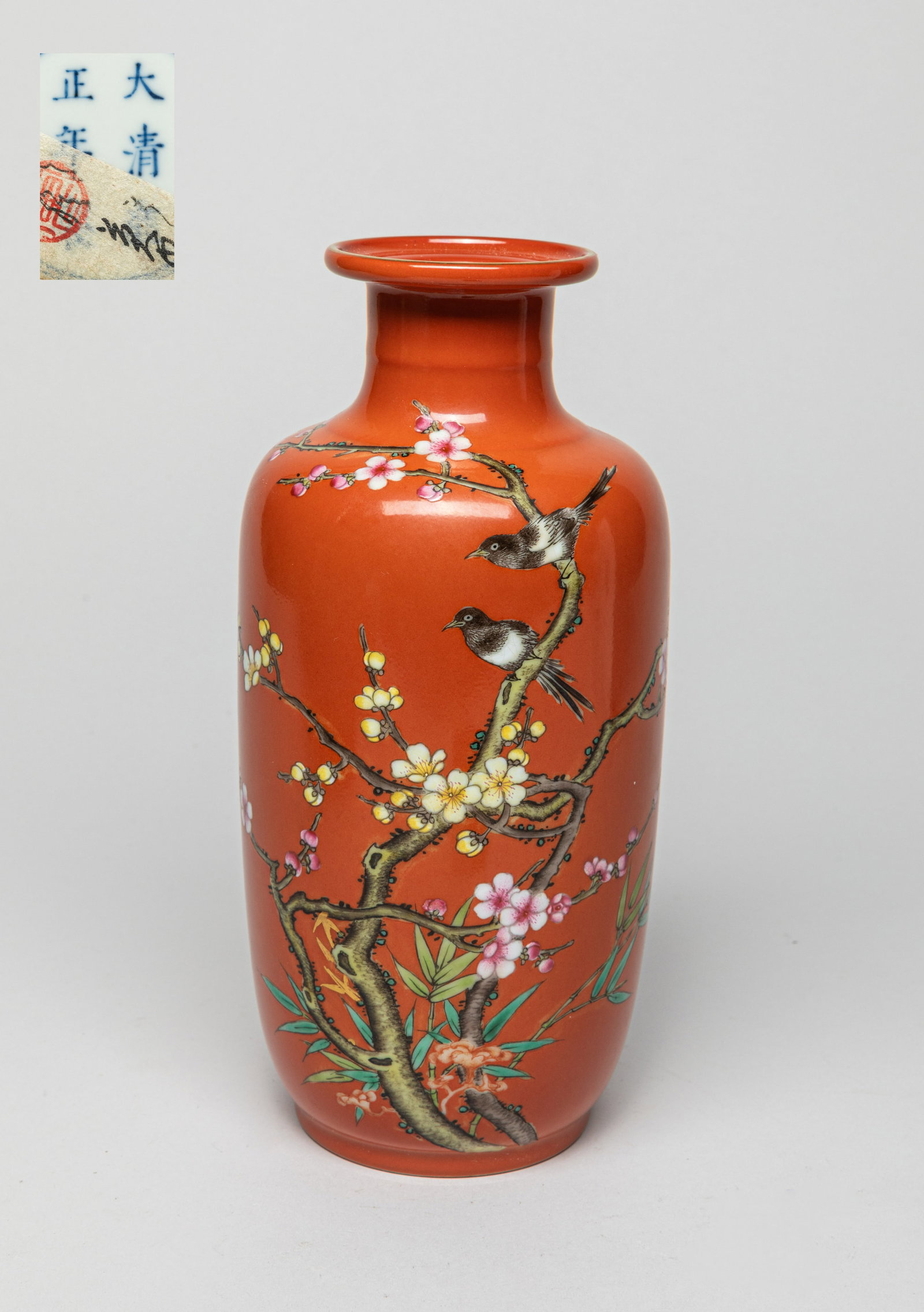 Chinese Famille Rose Porcelain Vase: Potted cylindrical body rising to a short neck under a curvy rim, painted with two birds on plum blossom branches on a brown color ground. The bottom with six-character mark enclosed within double cir