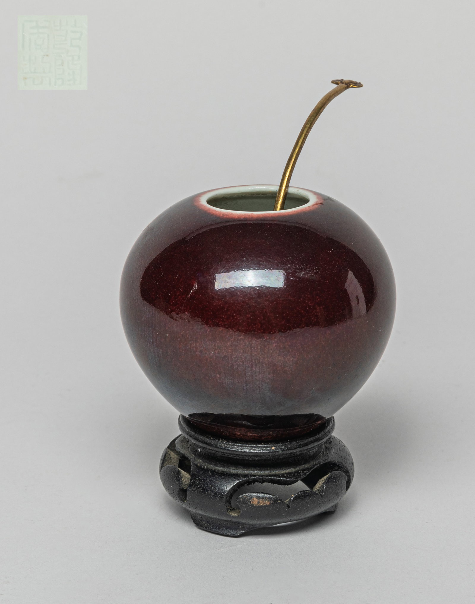 Chinese Flambe Glazed Porcelain Water Pot: One collectible water pot covered in dark red glaze. The bottom with a four character mark. With a brass spoon, and a stand. Approx. 2.6-2.3 inches (Pot Only).