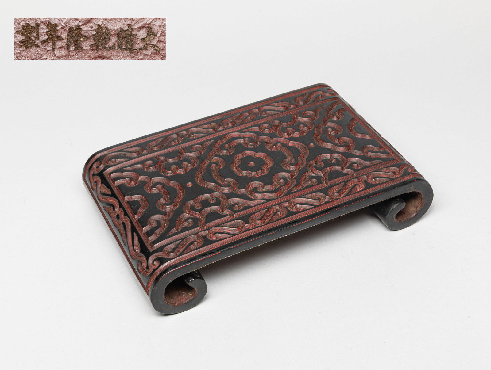 Chinese Carved Cinnabar Stand: Of rectangular form with two curved sides, the cinnabar stand carved with archaistic patterns. Approx. 11.2-7.2-2.2 inches.