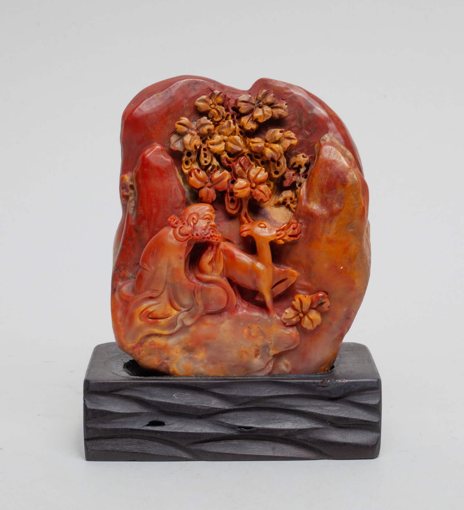 Chinese Shoushan Stone Sculpture: The sculpture carved with a seated male beside a deer with a flower tree in the background, with a stand. Approx. 3.5-1.2-4.1 inches.