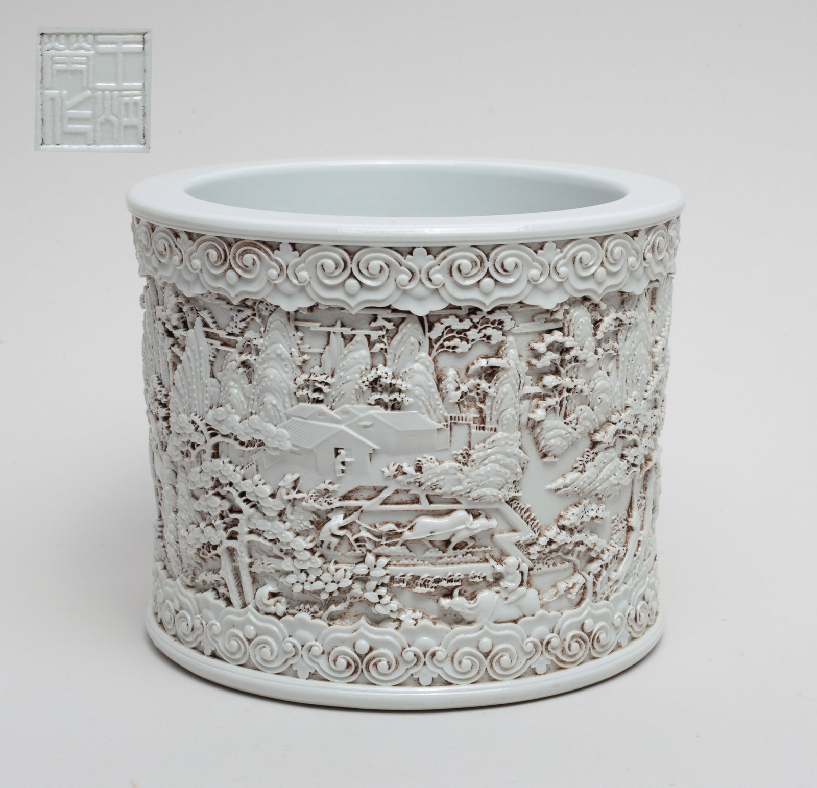 Chinese Blanc De Porcelain Brush Pot: The exterior carved in high relief: figures on a boat at a landscape setting, the rim and foot with a band of cloud motif. The bottom with a seal mark. Approx. 5.7–4.7 inches.