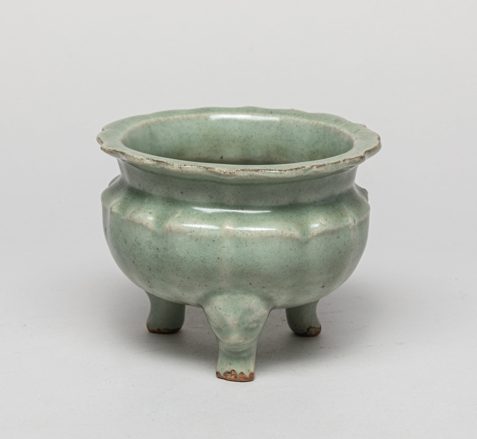 Chinese Early Type Porcelain Censer: The censer of the compressed globular body rising from three short feet to a broad lobed rim, applied in mottled celadon glaze stopping at the foot. Approx. 5-3.8 inches