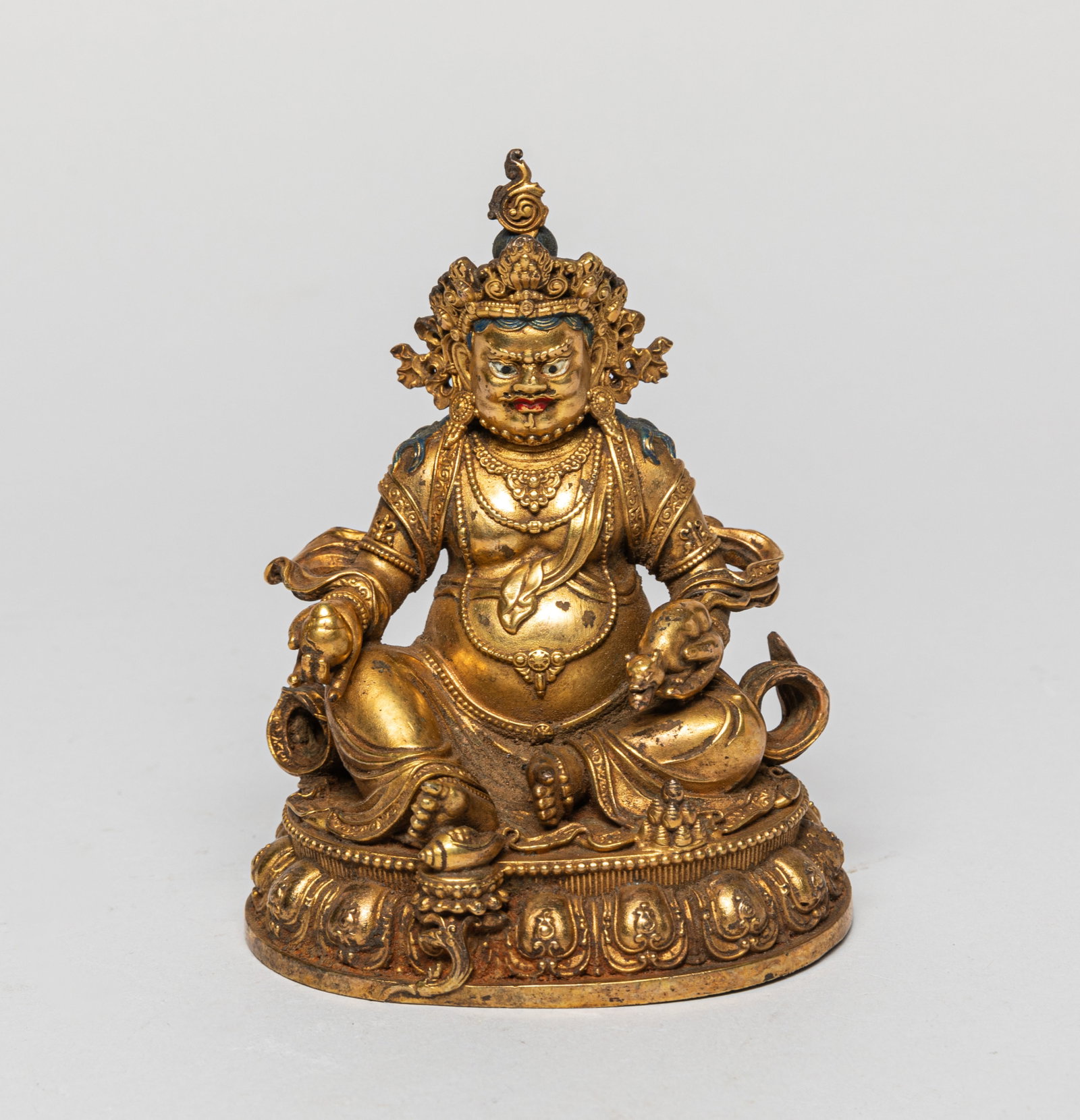 Chinese Sino-Tibetan Gilt Bronze Buddha: Seated in rajalilasana with the right arm rested on the raised right leg, supported on a lotus base, the chest adorned with beaded necklaces. Approx. 4.11-3.08 inches