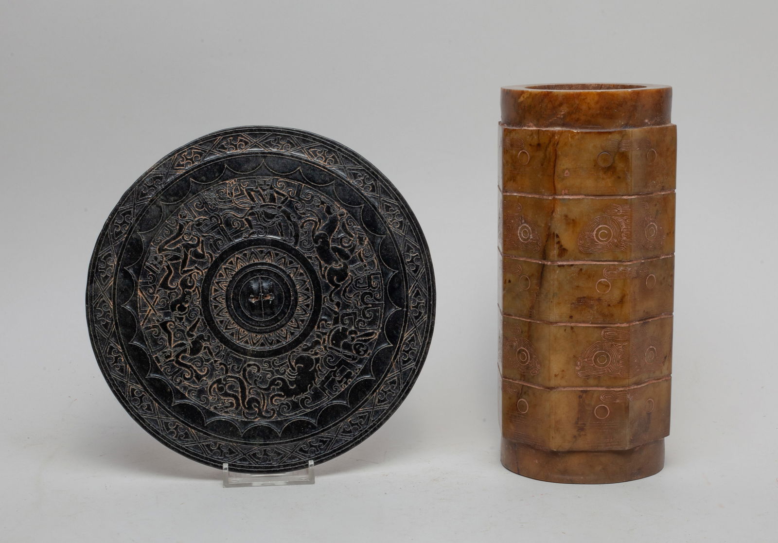 Chinese Jade/ Stone Carvings: One of flat circular form, carved with figures and beasts, the other of cylindrical octagonal section, carved in low relief with archaic masks. Approx. 8.3*4 inch (larger).