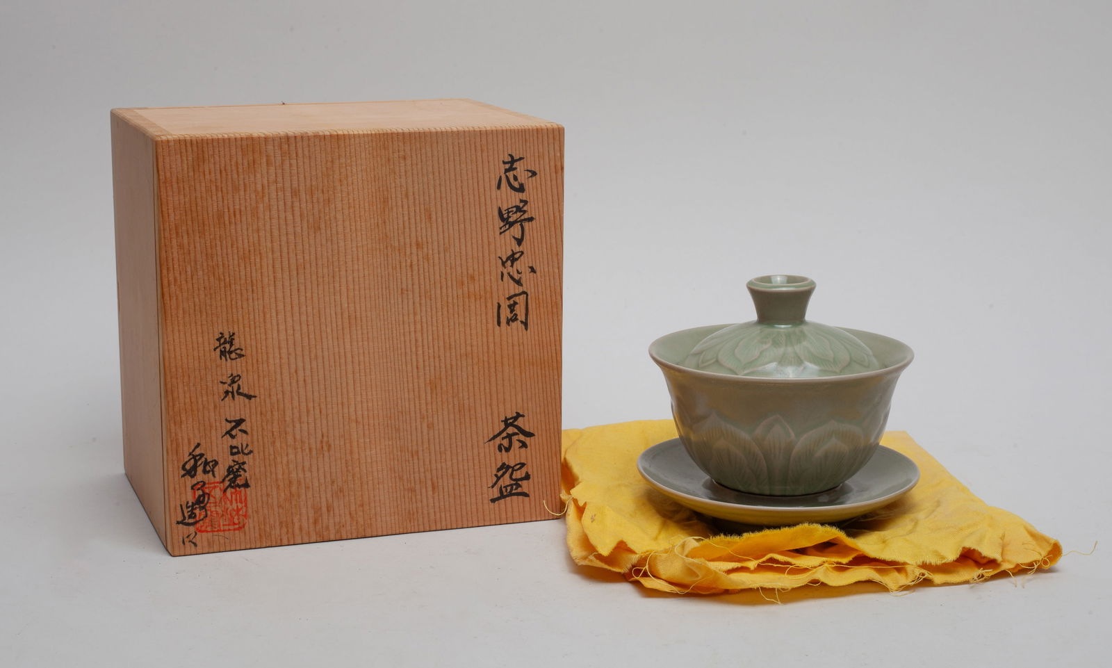 Chinese Longquan Porcelain Tea Cup: The tea cup exterior carved with lotus petals, the same design applied to the cover and the saucer, all covered with soft olive green glaze, with a box. Approx. 4.4-4.0 (Total, W/O box).
